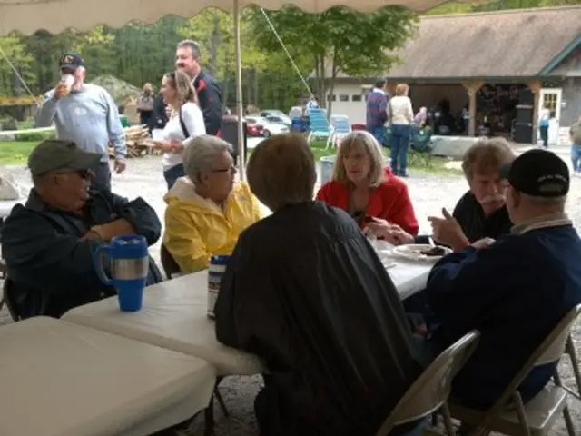 There is a cafe, inside that there are two white color tables and there are total six people...
